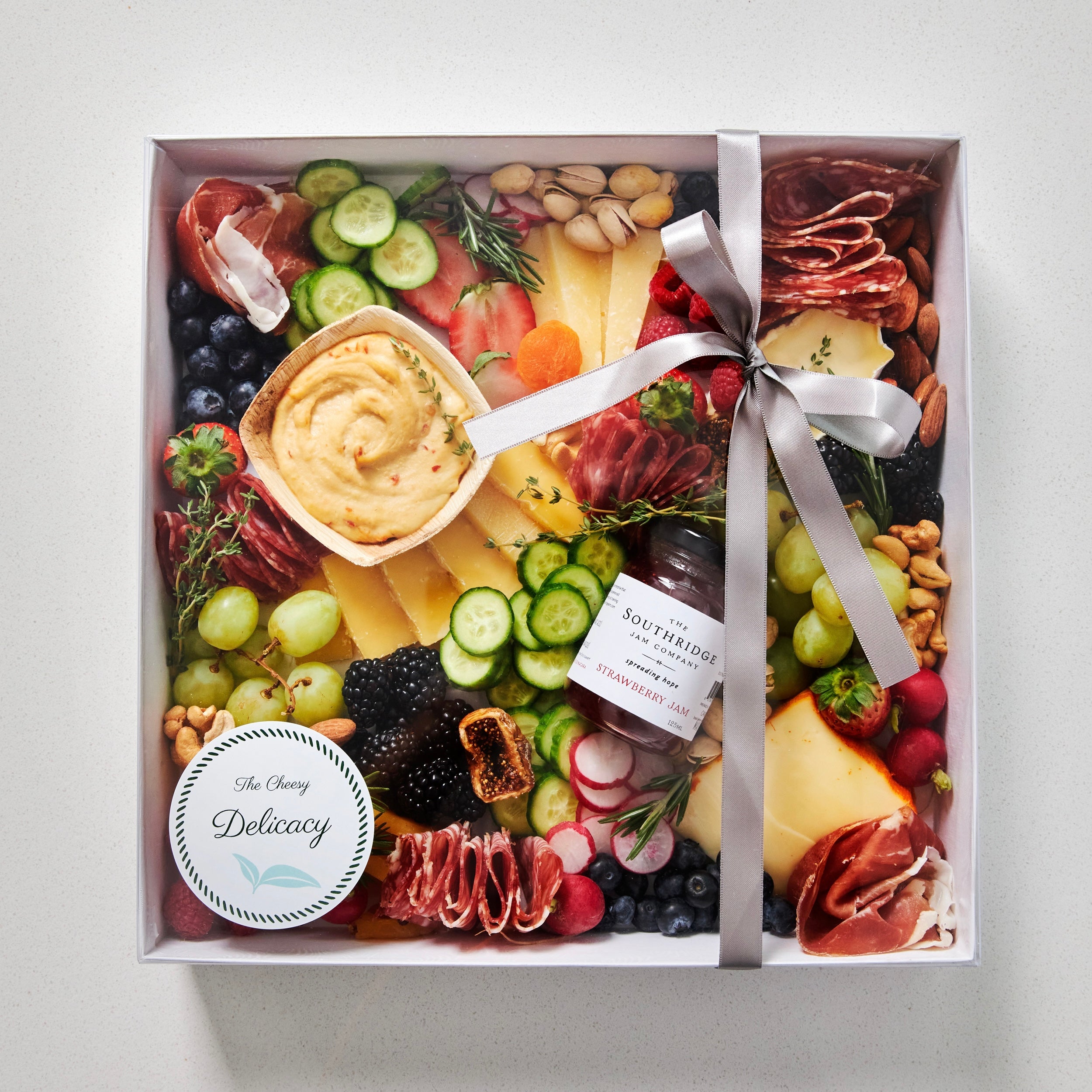 large grazing box with cheese, charcuteries, fruits, vegetables, hummus and jam - packaged